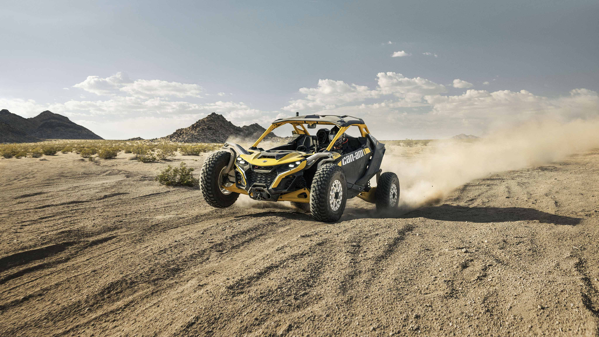 Een rijder in een Can-Am Maverick R die in de woestijn rijdt