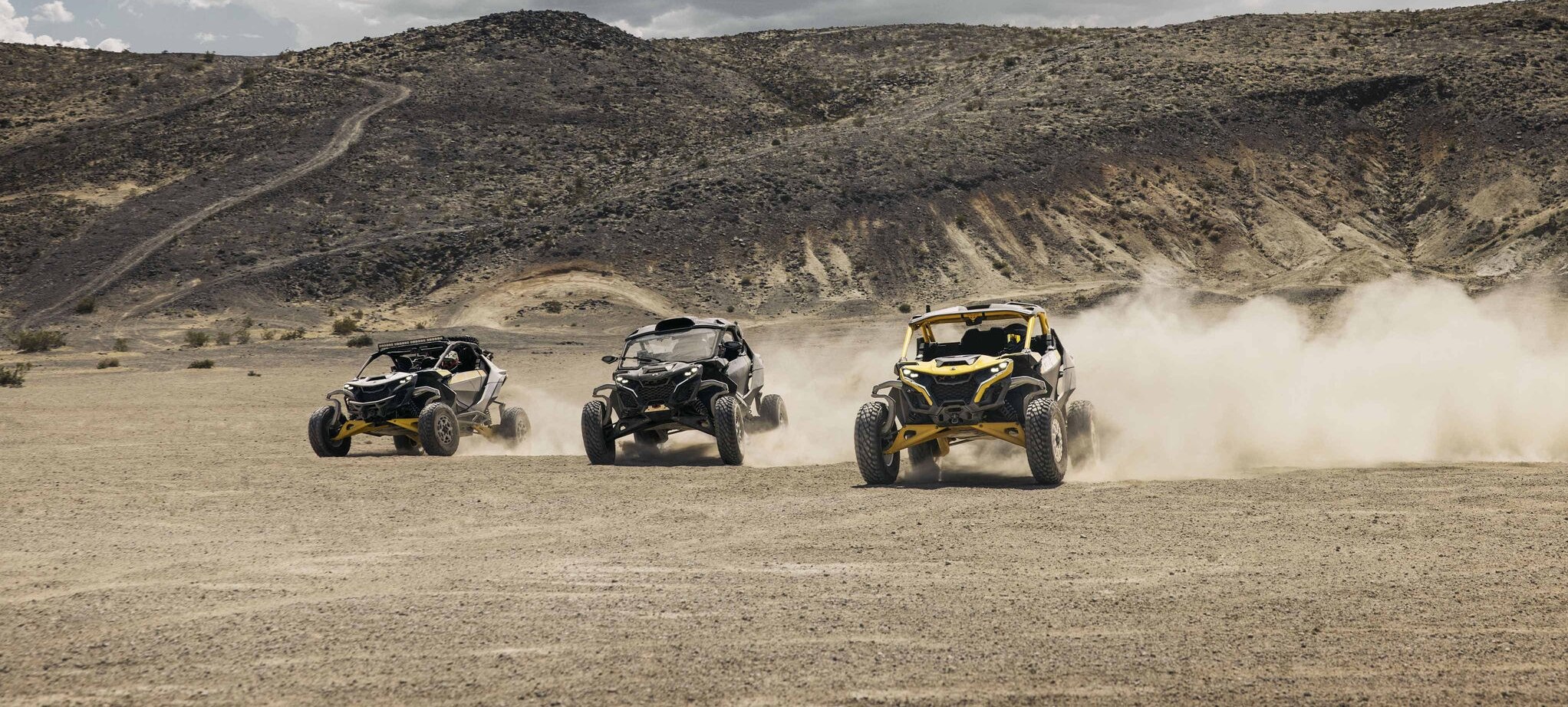 Drie Can-Am Maverick R SSV-voertuigen rijden door de woestijn.