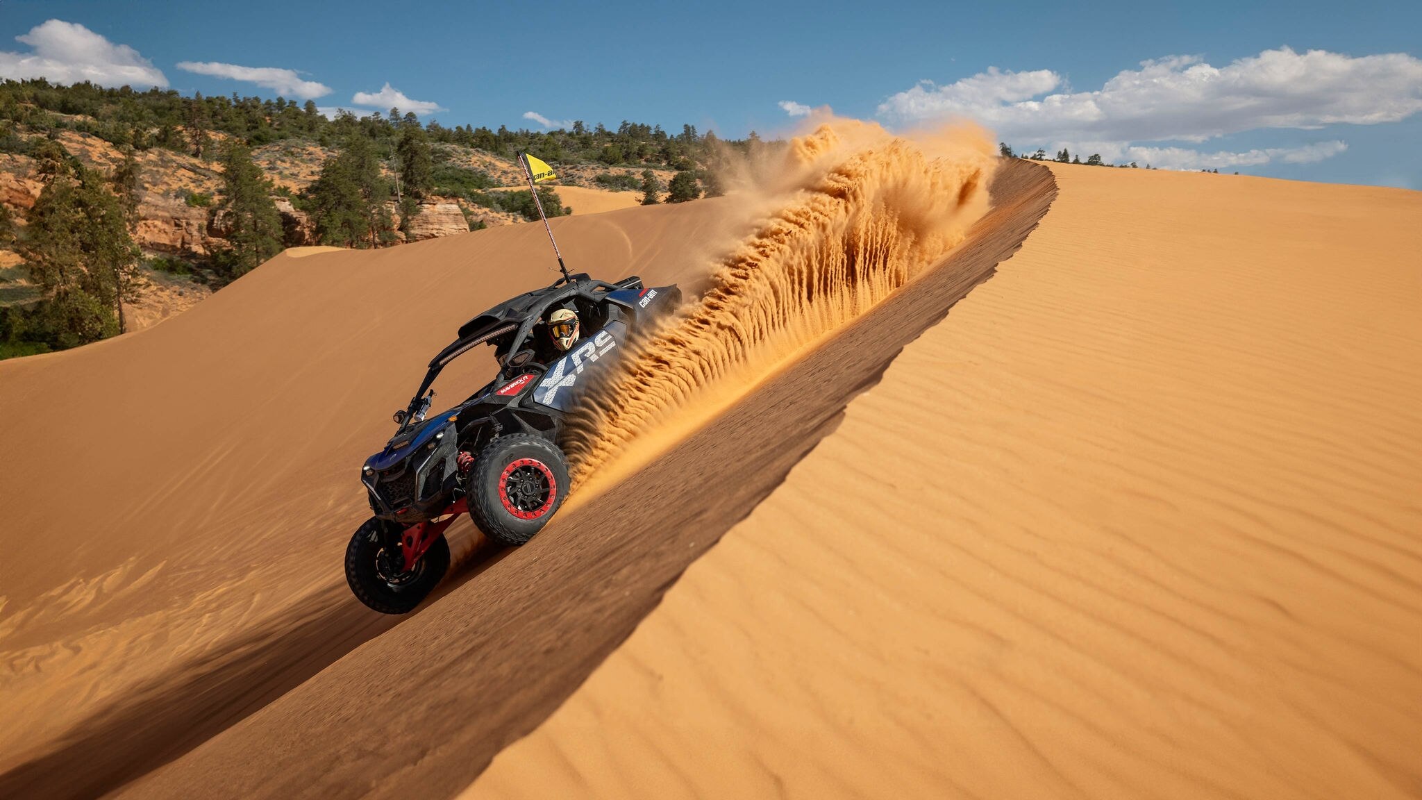 Can-Am Maverick R X RS 2025 pilotado em uma duna em um dia ensolarado