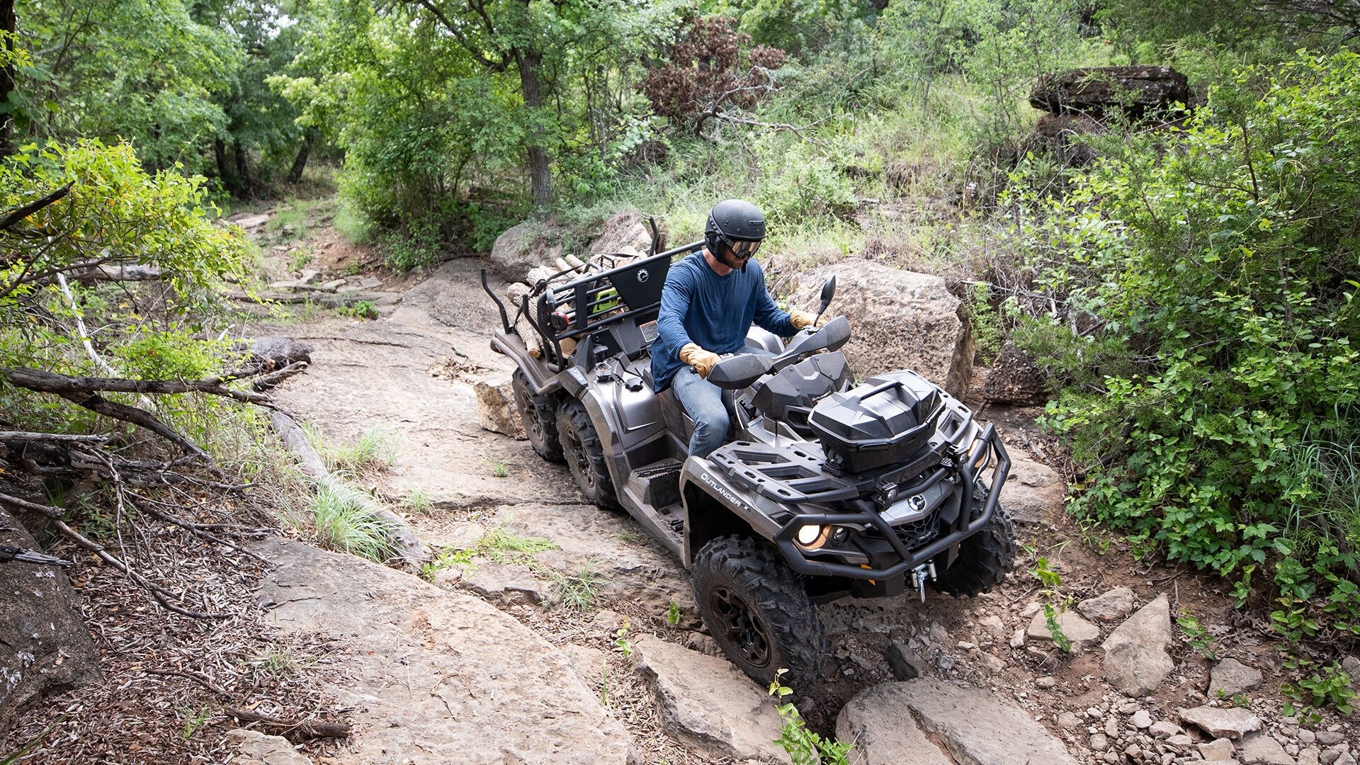 Vista aérea de un Can-Am Outlander 6x6 cargado de madera sobre un entorno rocoso. 