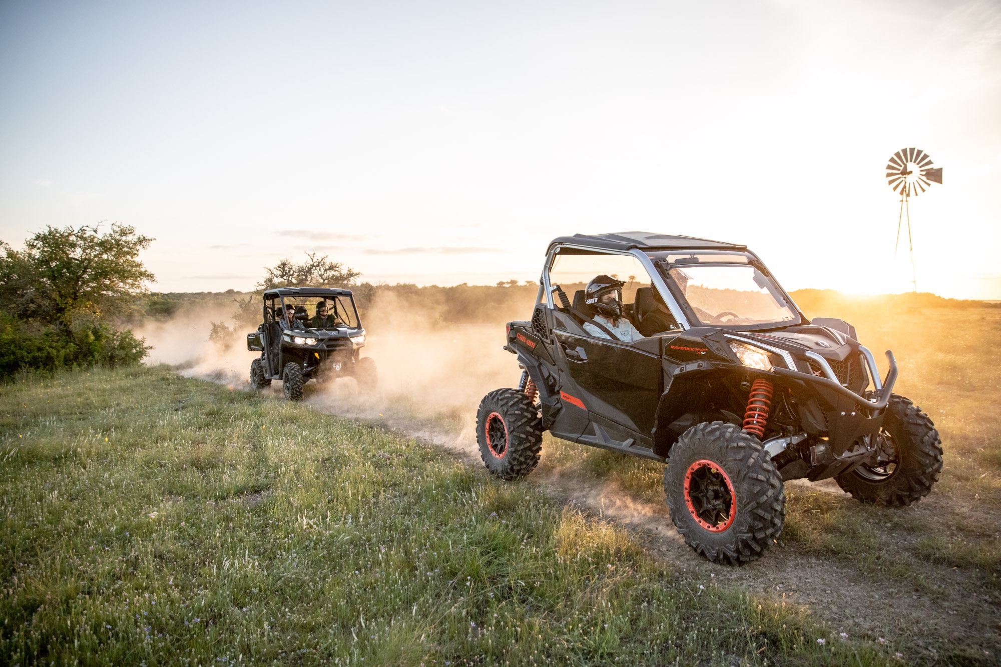 Two Can-Am side-by-side vehicless driving one after the other on the road to a ranch