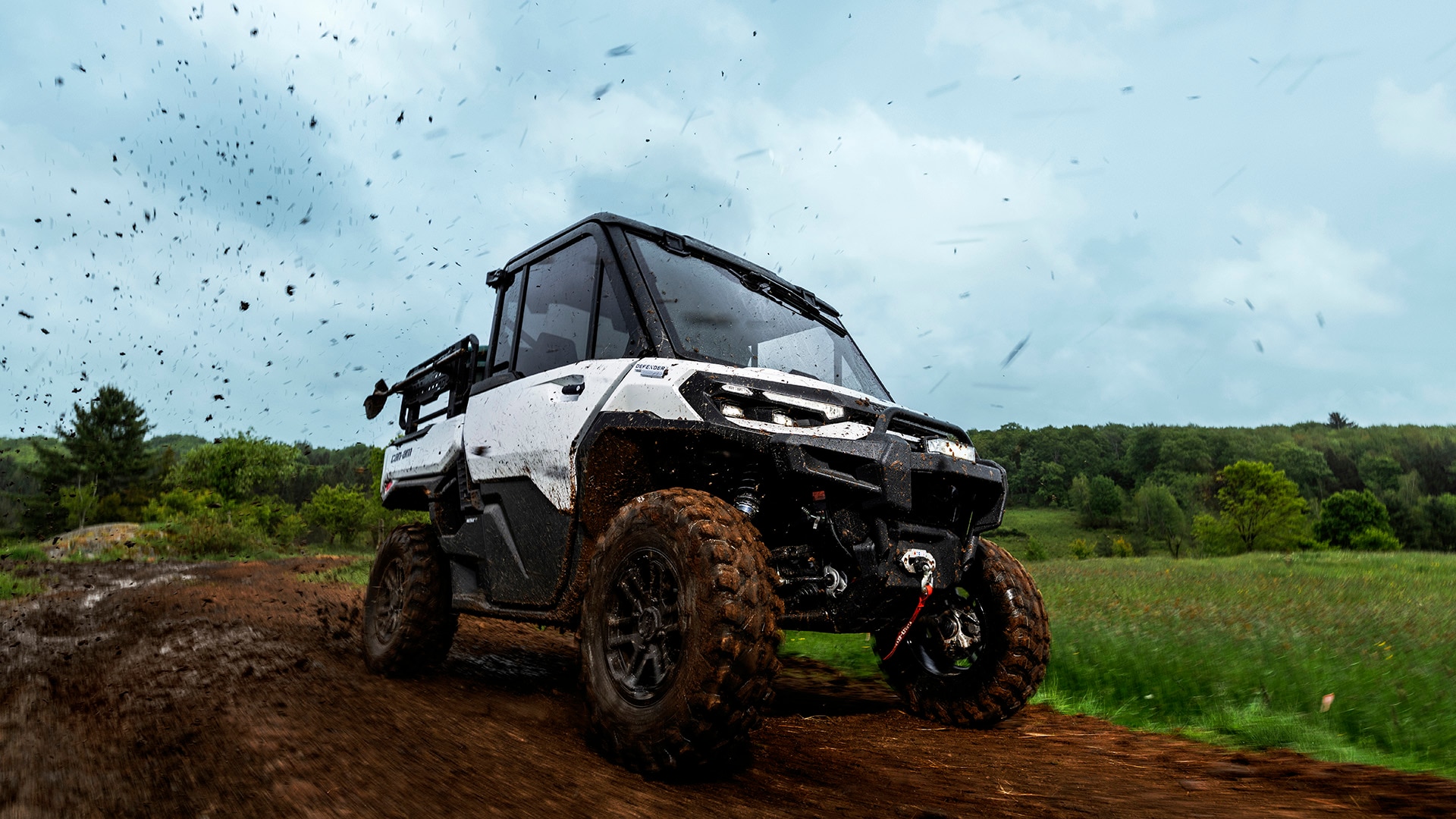 2026 Can-Am Defender HD11 Hybrid Blanco conduciendo por un camino de tierra