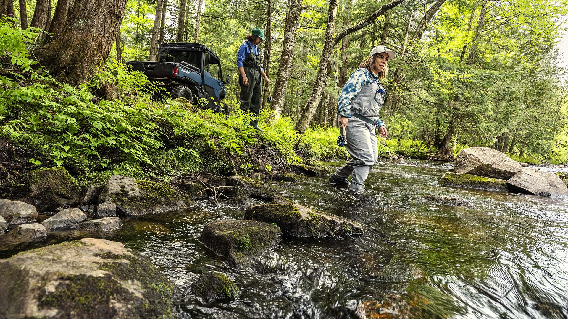2026 Can-Am Defender XT polvoriento navy side-by-side aparcado cerca del agua en el bosque