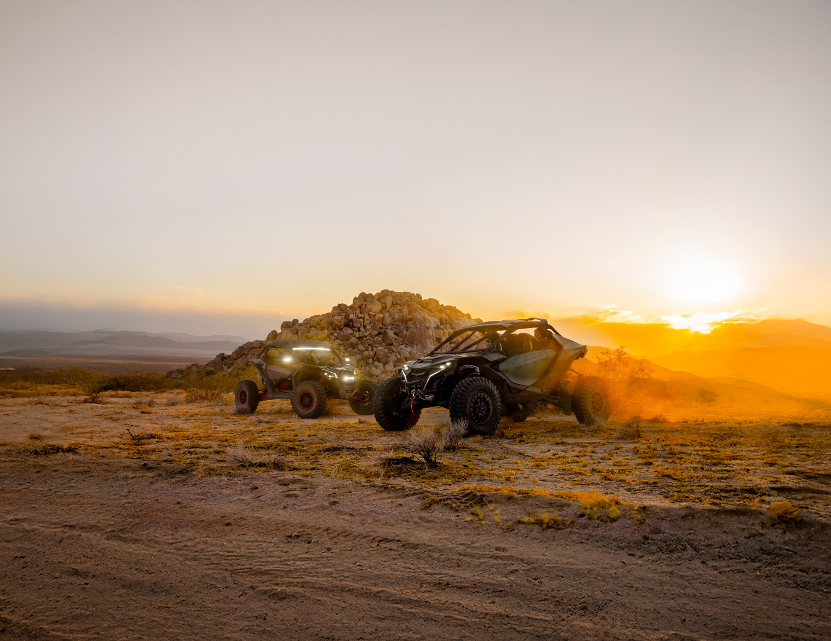 Dos Can-Am Maverick side-by-side en el desierto con una puesta de sol