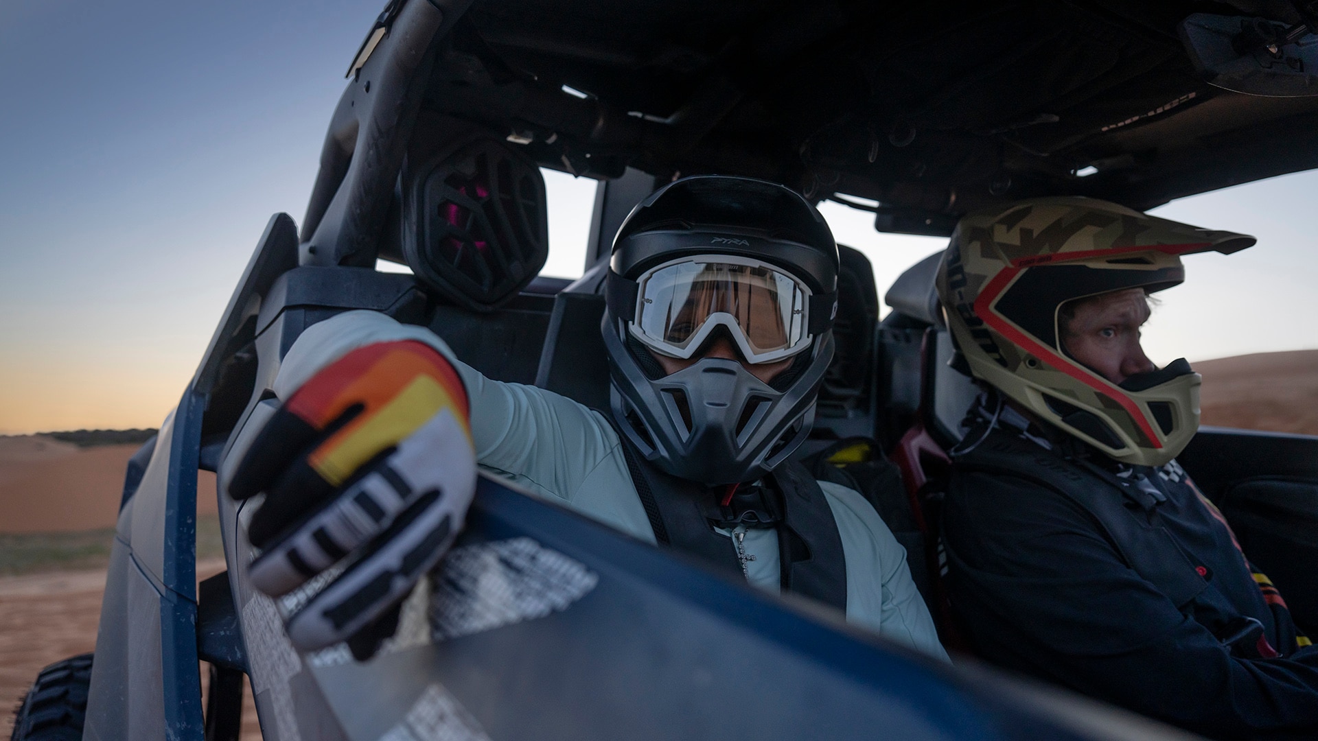 Two fully equipped drivers wearing Can-Am clothing inside a Can-Am Maverick R X RS SAS