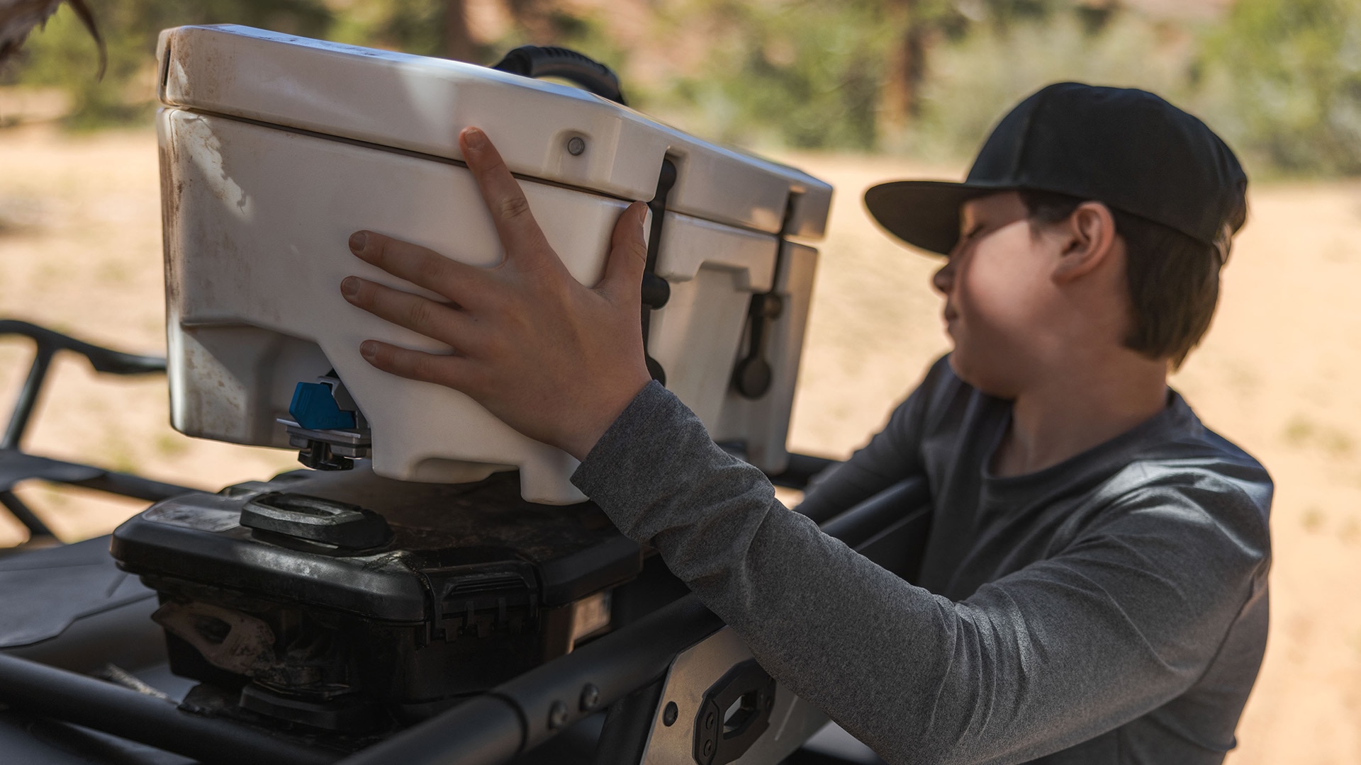 Young men installing a LinQ cooler on top of a side-by-side