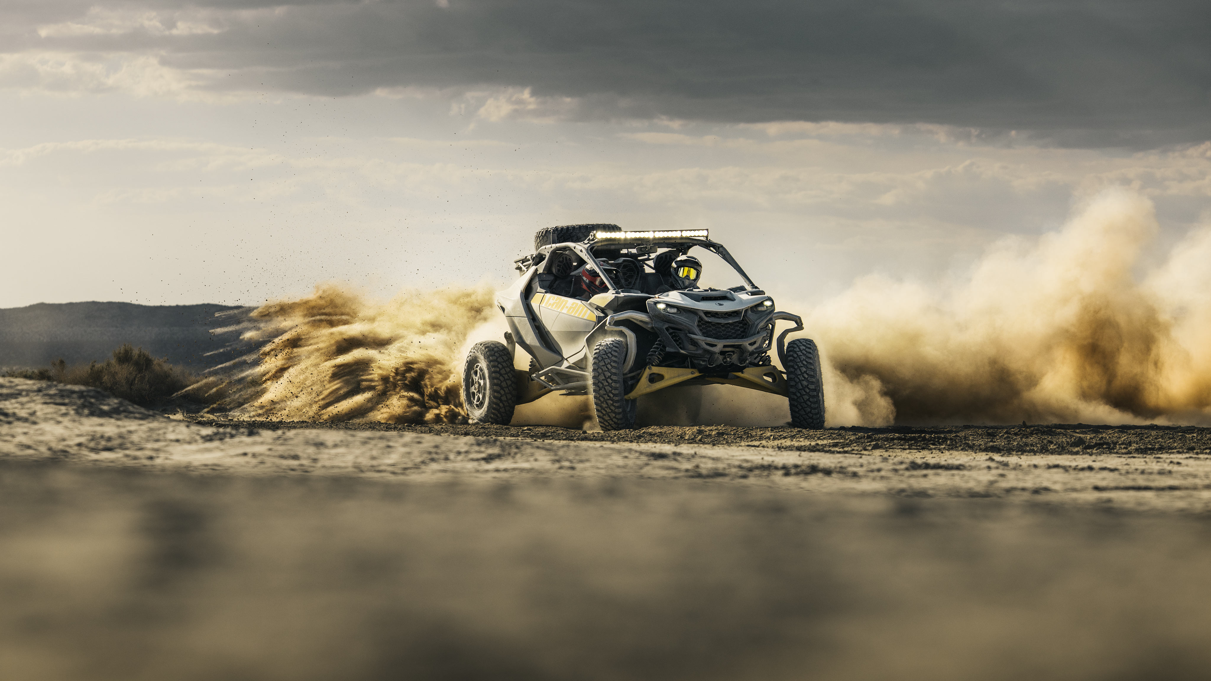 A rider driving a Can-Am Maverick R at high speed in the desert