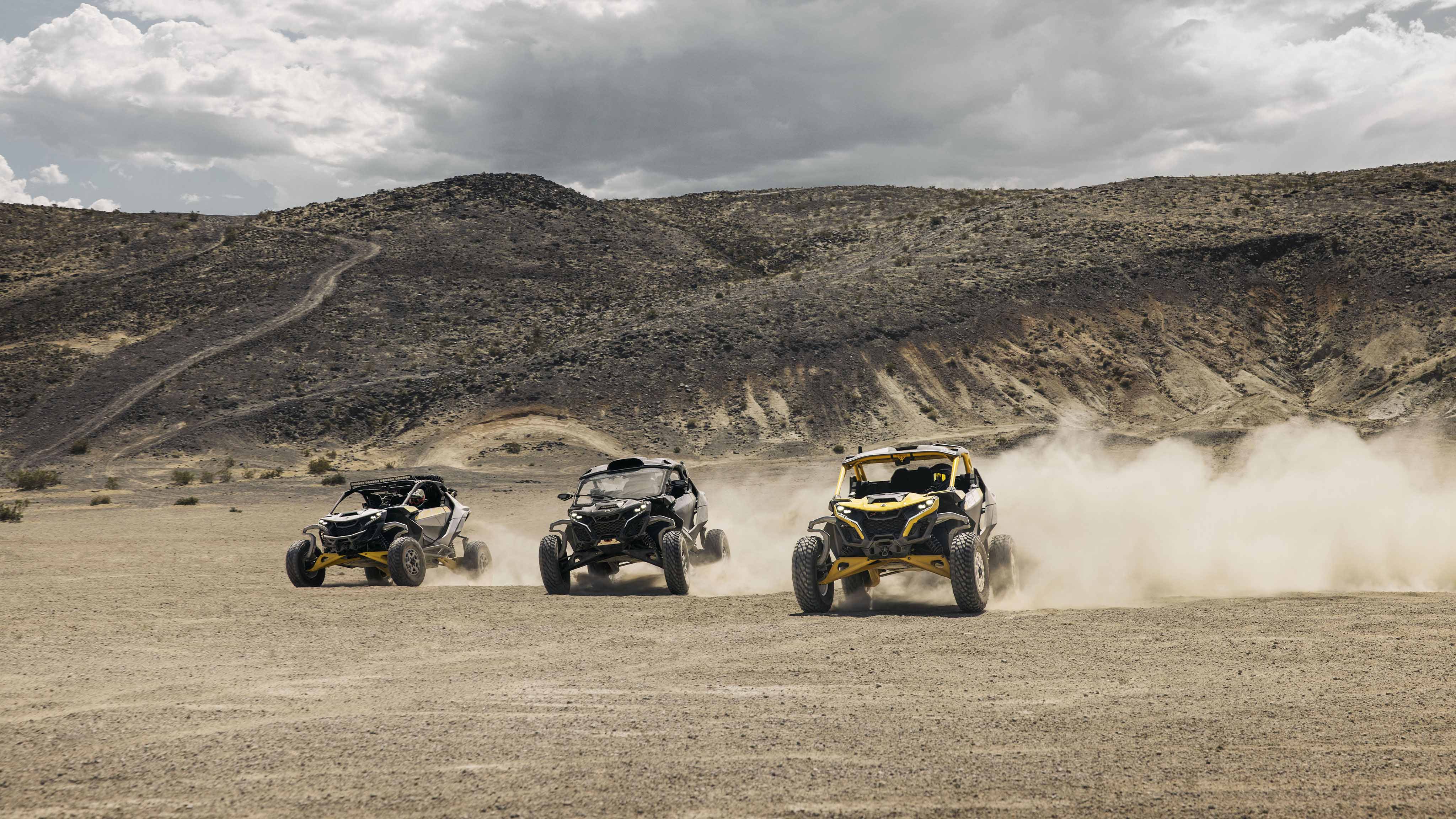Three Maverick R SxS vehicles racing through the desert